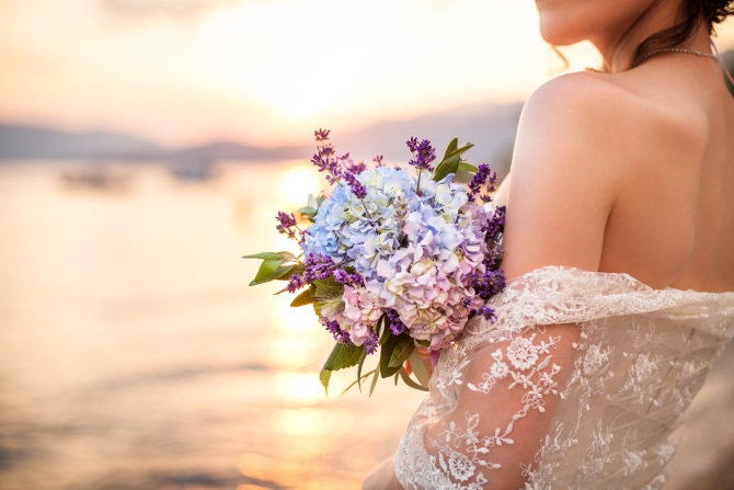 bride holding bouquet near the ocean
